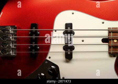 Directement sur la photographie de cordes et de ramasseurs sur une guitare basse rouge Banque D'Images