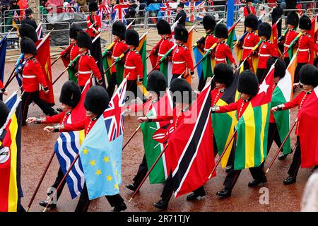 Angleterre, Londres, The Mall, Grenadier Guards défilant avec des drapeaux des pays du commonwealth pendant le couronnement du roi Charles III sur un M pluvieux Banque D'Images