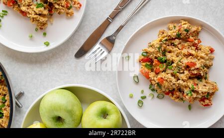 Riz brun frit avec œufs de brouille, thon et légumes sur des assiettes sur fond blanc Banque D'Images