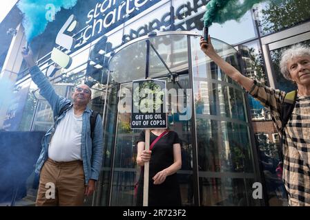 Londres, Royaume-Uni. 12 juin 2023. Les activistes du climat ont fait des éruptions de fumée devant les bureaux de la Standard Chartered Bank lors d'une matinée de manifestations dans la City de Londres contre les financiers des combustibles fossiles et l'influence des « grandes compagnies pétrolières » sur les prochaines négociations climatiques de COP28. Crédit : Ron Fassbender/Alamy Live News Banque D'Images