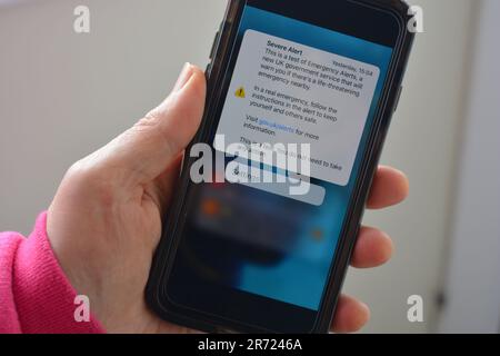 Téléphone portable en main avec écran montrant le texte reçu hier, de test pour alerte grave, il s'agit d'un test d'alertes d'urgence, un nouveau service gouvernemental Banque D'Images