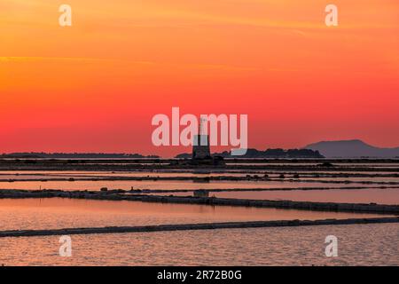 Coucher de soleil sur les appartements de sel avec l'ancien moulin à vent, saline dello Stagnone. Marsala, Trapani, Sicile, Italie, Europe. Banque D'Images