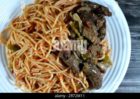 Une assiette de saucisses de bœuf cuites au Moyen-Orient, saucisses égyptiennes aux poivrons verts, oignon, ail, tomate, poivre noir et huile et spaghetti classiques Banque D'Images