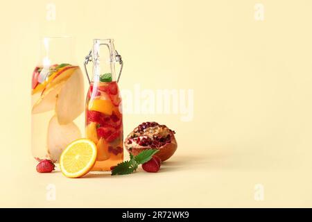 Bouteilles d'eau infusée avec différentes tranches de fruits sur fond beige Banque D'Images