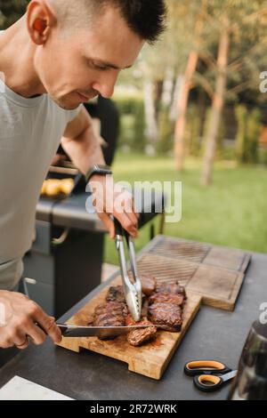 Un homme de la rue a cuit un steak sur le grill dans un barbecue. Banque D'Images