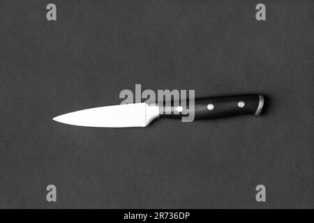 Couteau de cuisine avec poignée noire sur fond noir. Couteau sur fond sombre vue de dessus. Ustensiles de cuisine. Couteau à lame large. Banque D'Images