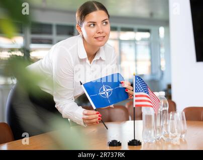 Réunion des relations internationales. Fille qui pose des drapeaux de l'OTAN et des États-Unis sur la table Banque D'Images