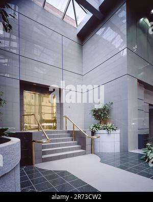 Atrium de bureau moderne avec lucarne en verre, murs en pierre polie, plantes intérieures, réception et design architectural contemporain. Banque D'Images