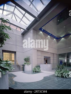 Atrium de bureau moderne avec lucarne en verre, murs en pierre polie, plantes intérieures, réception et design architectural contemporain. Banque D'Images