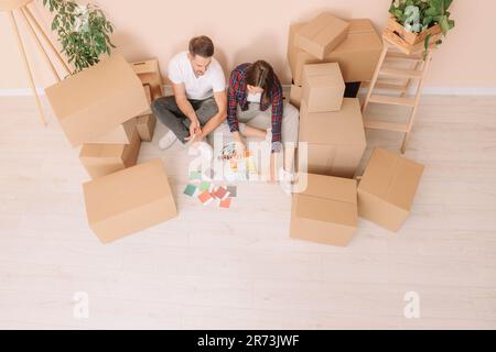 Un couple heureux entouré de boîtes mobiles en choisissant les couleurs dans le nouvel appartement, au-dessus de la vue Banque D'Images