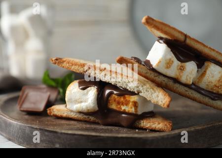 Délicieux sandwiches guimauves au chocolat sur plateau en bois, gros plan Banque D'Images