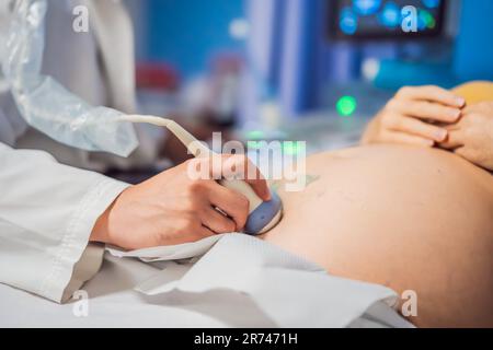 À l'hôpital, la prise de vue rapprochée du médecin effectue une procédure d'échographie à une femme enceinte. Capteur de mouvement obstétricien sur le ventre de Banque D'Images