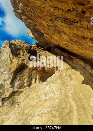 Un sentier de montagne sinueux avec de grandes formations rocheuses et une petite entrée de grotte au fond Banque D'Images