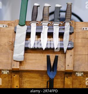 De nombreux couteaux sont disposés sur la barre de coupe. Couteaux militaires pour l'armée, ensemble Banque D'Images