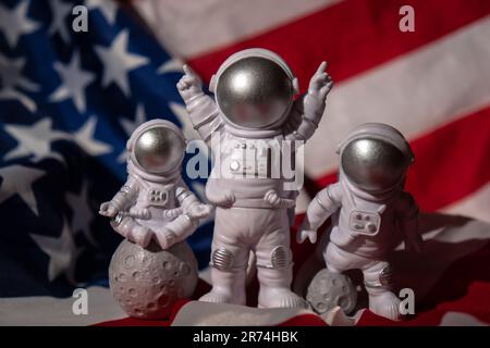 Trois jouets en plastique figurent astronaute sur le drapeau américain arrière-plan espace de copie. 50th anniversaire des États-Unis atterrissage sur la Lune concept de voyage hors terre, vols commerciaux privés de spaceman. Missions spatiales et durabilité Banque D'Images