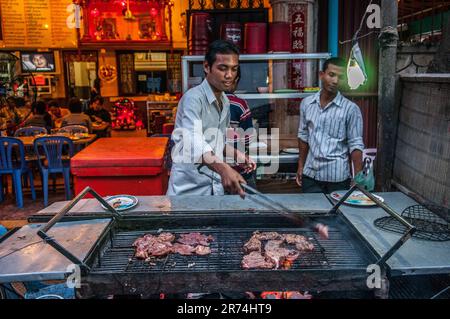 2 hommes cambodgiens grillant de la viande dans un restaurant barbecue en plein air local. Phnom Penh, Cambodge. © Kraig Lieb Banque D'Images