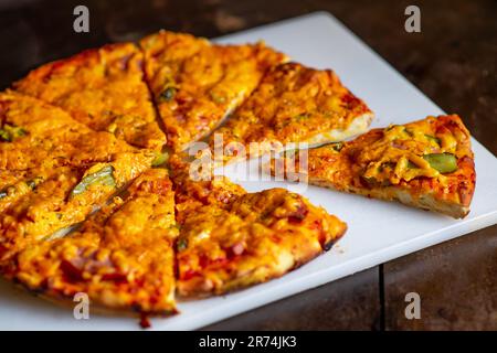 Tranches de pizza sur une planche à découper blanche. Banque D'Images