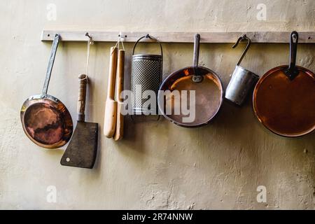 Un assortiment d'ustensiles de cuisine et de vaisselle, y compris suspendus sur un mur de manière organisée Banque D'Images