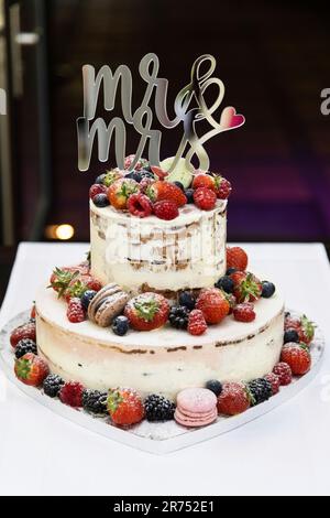 Gâteau de mariage à deux niveaux avec macarons et fruits aux baies Banque D'Images