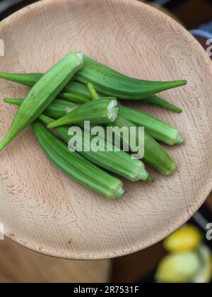 une femme africaine hache des légumes aux fruits d'okra pour cuisiner une recette traditionnelle avec d'autres légumes et fruits locaux. Banque D'Images