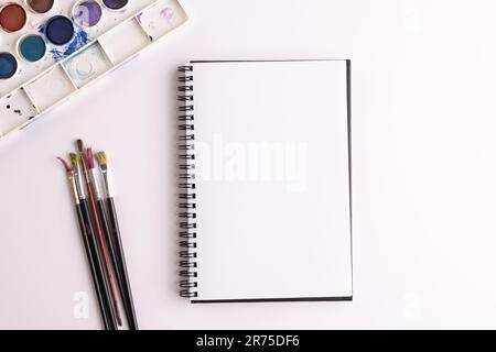 Gros plan de peintures, carnets et pinceaux avec espace de copie sur fond blanc. Retour à l'école, art, peinture, matériel scolaire, apprentissage, école et ed Banque D'Images