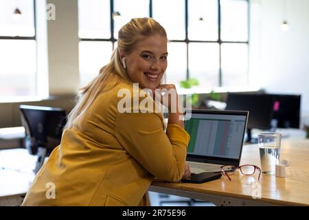 Portrait de femme d'affaires caucasienne heureuse de taille plus décontractée avec ordinateur portable au bureau Banque D'Images