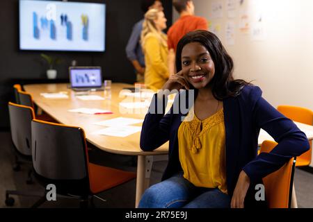 Portrait d'heureuse femme d'affaires afro-américaine occasionnelle dans la salle de réunion avec divers collègues Banque D'Images