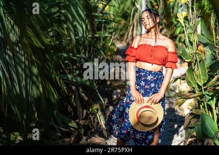 Amérique du Nord, Caraïbes, Grande Antilles, Île d'Hispaniola, République dominicaine, Province de SAMA, Péninsule de Sama, El Limón, Sama Eco Lodge, jolie Latina sur un chemin de gravier ombragé dans le jardin tropical. Banque D'Images