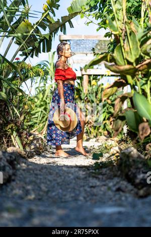 Amérique du Nord, Caraïbes, Grande Antilles, Île d'Hispaniola, République dominicaine, Province de SAMA, Péninsule de Sama, El Limón, Sama Eco Lodge, jolie Latina sur un chemin de gravier ombragé dans le jardin tropical. Banque D'Images