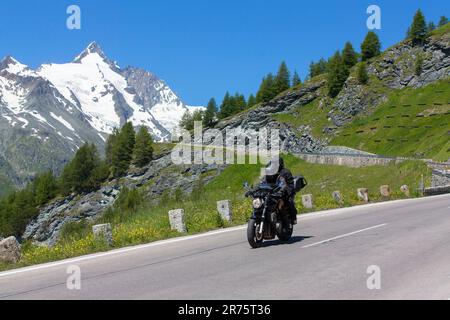 Motocycliste sur la route haute de Großglockner, vue vers la neige couverte Großglockner et Kaiser-Franz-Josefs-Höhe Banque D'Images