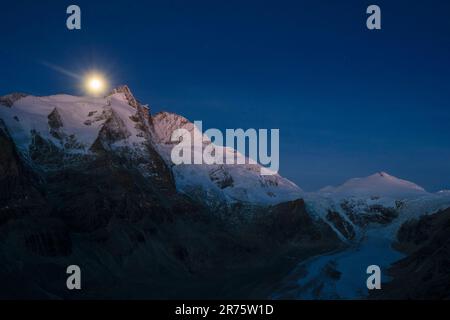 Début sur Großglockner, vue sur le groupe Glockner, Pasterze et Johannisberg, heure bleue, pleine lune brille à côté du sommet et illumine la chaîne de montagnes enneigée Banque D'Images