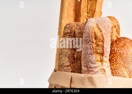 Différents types de baguettes de pain français dans un sac de papier sur fond blanc avec espace de copie. Boulangerie, cuisine délicieuse concept Banque D'Images