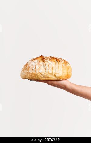 Pain multigrain fait maison dans la main de femme sur fond blanc. Boulangerie, concept alimentaire Banque D'Images