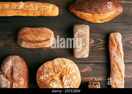 Différents types de pains sur fond de bois sombre. Boulangerie, cuisine délicieuse concept Banque D'Images