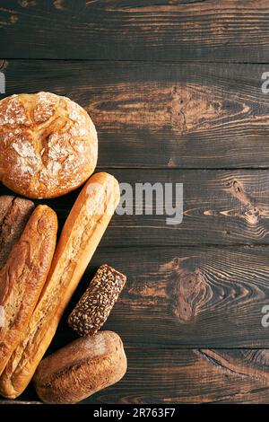 Différents types de pains sur fond en bois avec espace de copie. Boulangerie, cuisine délicieuse concept. Vue de dessus Banque D'Images