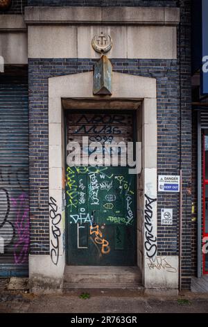 Un gros plan d'une porte extérieure dans un cadre urbain recouvert de graffiti. Banque D'Images