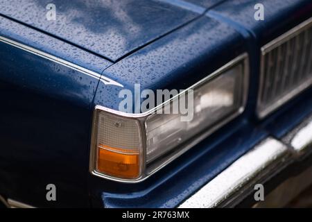 Izmir, Turquie - 3 juin 2023 : gros plan du phare unique sur un Caprice de Chevrolet bleu, peut-être un modèle 1978, orné de gouttes de pluie Banque D'Images