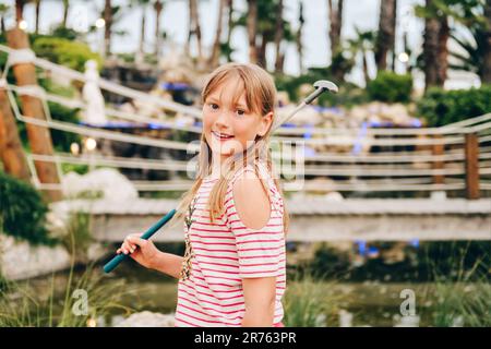 Drôle enfant fille jouant au mini-golf, enfant appréciant les vacances d'été Banque D'Images