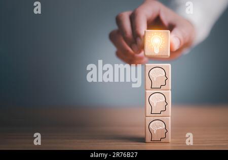 brainstorming idée créative et innovation. Main mettant sur le bloc de cube en bois avec l'icône d'ampoule sur beaucoup de personnes ensemble ayant une idée symbolisée Banque D'Images