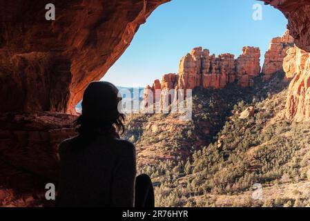 Une jeune femme se tenant au sommet d'un point de vue de roche rouge dans les montagnes, Sedona, Arizona Banque D'Images