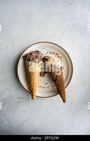 Vue de dessus des cornets de gaufres avec café et glace au chocolat avec des saupoudrés de sucre multicolore et des noix sur un plat en céramique Banque D'Images