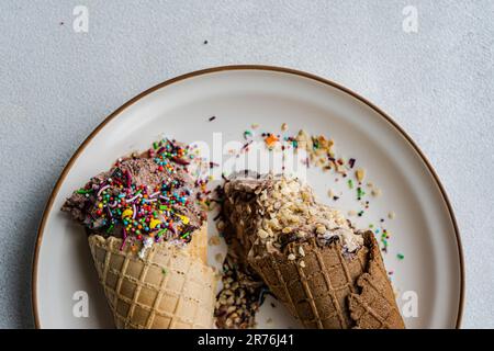 Vue de dessus des cornets de gaufres avec café et glace au chocolat avec des saupoudrés de sucre multicolore et des noix sur un plat en céramique Banque D'Images