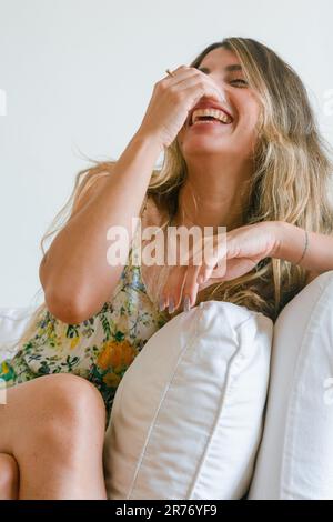 vue de face de la jeune femme latine d'origine colombienne appréciant la journée assise sur le canapé souriant heureux, style de vie concept, espace de copie. Banque D'Images