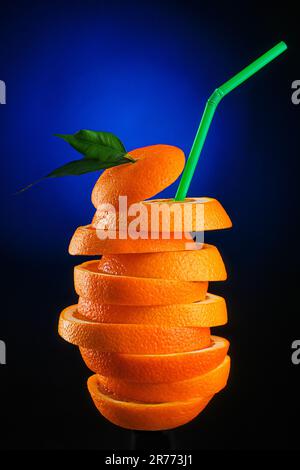 une pile d'oranges avec une paille verte sur fond sombre et rétro-éclairage bleu. Photo publicitaire de jus d'orange juteux. photographie en studio. Banque D'Images