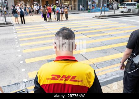 Un employé de messagerie de la société allemande de courrier express DHL est en route pour livrer des marchandises à Hong Kong. Banque D'Images