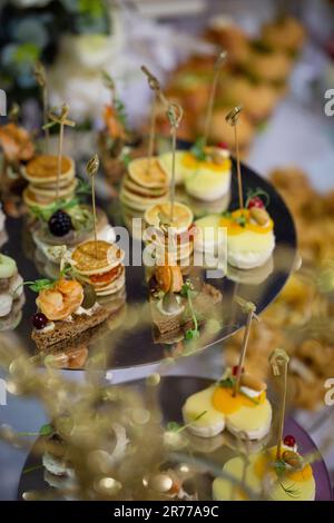 assortiment d'en-cas canapés sur un support en métal sur la table du buffet. Banque D'Images