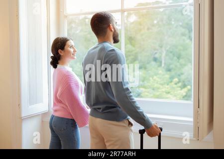 Vue latérale du couple de touristes près de la fenêtre dans l'intérieur de l'hôtel Banque D'Images