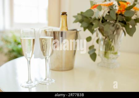 Verres et bouteille de vin mousseux sur table à l'intérieur Banque D'Images