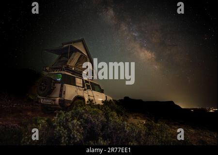 Camping romantique dans une tente sur le toit sur un 4x4 Offroad véhicule avec des étoiles et la manière laiteuse dans le ciel de nuit Banque D'Images