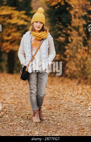 Portrait d'automne d'une adorable jeune fille de 10-11 ans, portant une veste en duvet grise, un chapeau jaune et un foulard Banque D'Images